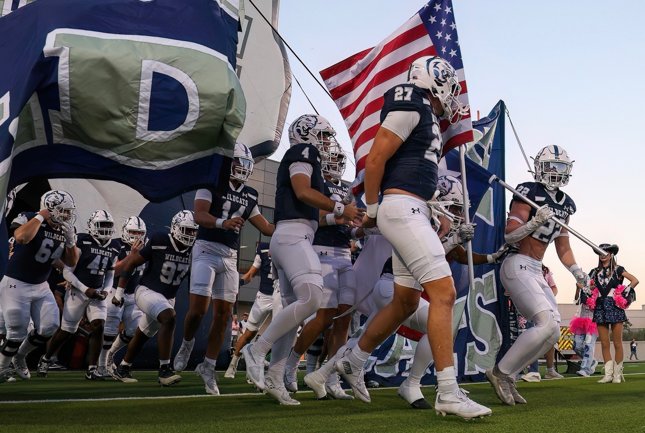 Walnut Grove football players, including Ashton number 4, entering the field with flags